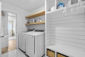 Laundry room with washing machine and clothes dryer, laundry area, and marble finish floor