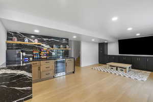 Bar featuring beverage cooler, light wood-type flooring, stairway, and recessed lighting