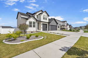 Modern farmhouse with a front lawn, a residential view, driveway, board and batten siding, and fence