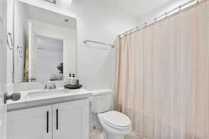 Full bath featuring toilet, curtained shower, tile patterned floors, and vanity