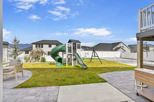 Community playground with a residential view, a lawn, a patio, and a fenced backyard