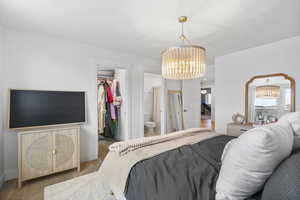 Bedroom featuring a chandelier, a closet, baseboards, wood finished floors, and a spacious closet