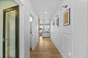 Hallway with light wood-style floors and recessed lighting