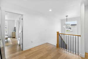 Corridor featuring recessed lighting, an inviting chandelier, light wood-style floors, an upstairs landing, and baseboards