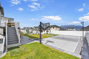 View of sport court with fence, a residential view, a mountain view, a playground, and a lawn