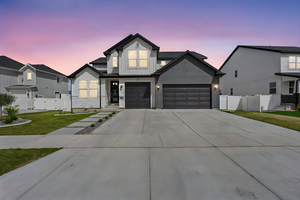 View of front of home featuring concrete driveway, a lawn, board and batten siding, and fence