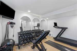 Workout area with wood finished floors, recessed lighting, baseboards, and arched walkways