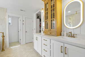 Bathroom featuring double vanity, tiled shower, brick floor, and a sink