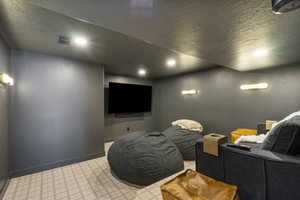 Cinema room featuring recessed lighting, a textured ceiling, visible vents, and baseboards