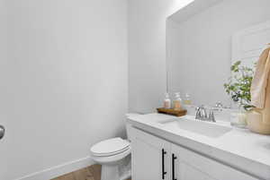 Bathroom with baseboards, wood finished floors, toilet, and vanity
