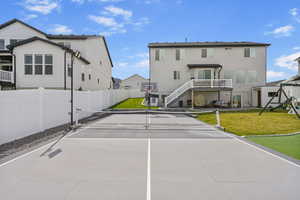 View of tennis court with fence, a yard, stairs, and a residential view