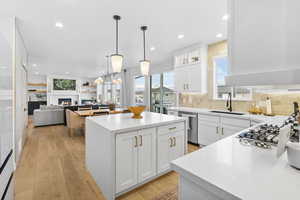 Kitchen with a sink, stainless steel appliances, a kitchen island, light countertops, and white cabinets