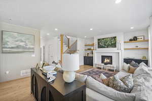 Living room featuring visible vents, light wood-type flooring, a textured ceiling, and baseboards