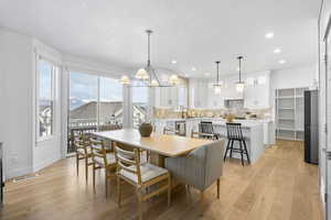 Dining area featuring a textured ceiling, visible vents, baseboards, and light wood-type flooring