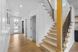 Staircase featuring hardwood / wood-style floors, recessed lighting, a textured ceiling, and baseboards