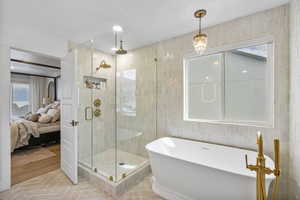 Full bathroom featuring tile walls, a freestanding bath, a shower stall, and ensuite bathroom