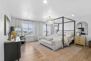 Bedroom with an inviting chandelier, a textured ceiling, recessed lighting, and light wood finished floors