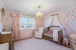 Bedroom with a wainscoted wall, crown molding, a notable chandelier, and wallpapered walls