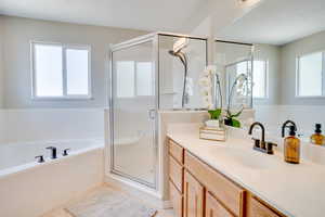 Bathroom with vanity, a bath, a shower stall, and plenty of natural light