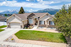 Single story home with stone siding, stucco siding, a mountain view, and an attached garage