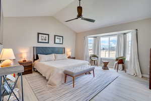 Bedroom with light wood-type flooring, vaulted ceiling, ceiling fan, and baseboards