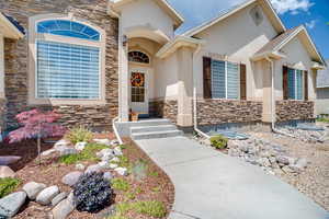 Entrance to property featuring stone siding and stucco siding