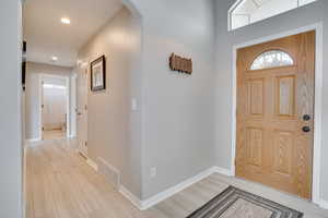 Entryway with arched walkways, light wood-style flooring, baseboards, and recessed lighting