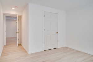 Empty room featuring light wood-style flooring, a smoke detector, baseboards, and recessed lighting