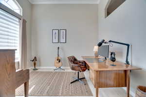 Office with ornamental molding, baseboards, and light wood-style flooring
