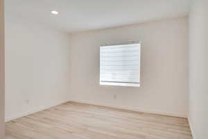 Empty room with light wood-style floors, recessed lighting, and baseboards