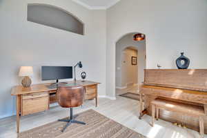 Office featuring ornamental molding, light wood-type flooring, baseboards, and arched walkways