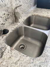 Details with a sink, light stone counters, and decorative backsplash