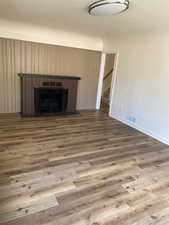 Unfurnished living room featuring stairway, visible vents, baseboards, a fireplace, and wood finished floors