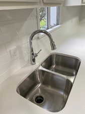 Details with a sink, light stone counters, and tasteful backsplash