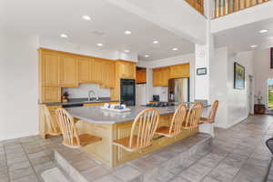 Kitchen featuring a breakfast bar area, stainless steel appliances, recessed lighting, and baseboards