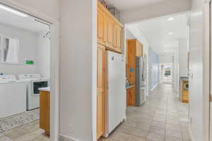 Hall featuring light tile patterned floors, recessed lighting, washer and dryer, and baseboards