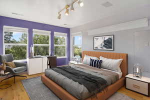 Bedroom featuring visible vents, light wood-type flooring, and rail lighting
