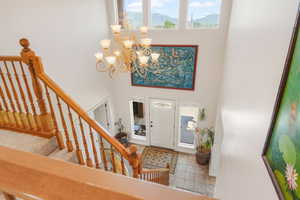 Foyer entrance featuring tile patterned flooring, a chandelier, baseboards, stairway, and a towering ceiling
