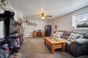 Carpeted living room featuring a textured ceiling and a ceiling fan