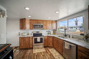 Kitchen featuring appliances with stainless steel finishes, dark wood-type flooring, and brown cabinets