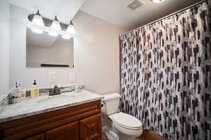 Bathroom featuring visible vents, toilet, curtained shower, and vanity