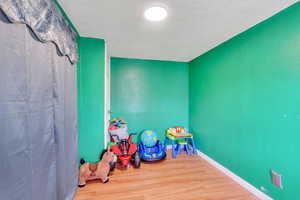 Playroom featuring a textured ceiling, wood finished floors, and baseboards