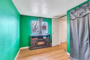 Interior space with a textured ceiling, wood finished floors, and baseboards