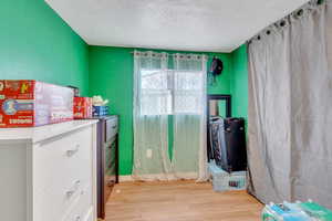Miscellaneous room featuring a textured ceiling and light wood-type flooring