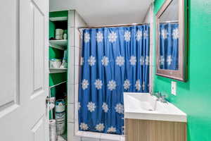 Full bath featuring curtained shower and vanity