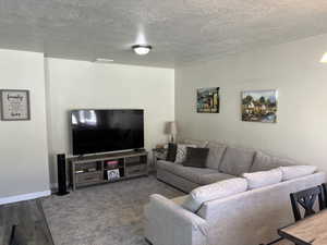 Living room featuring baseboards, visible vents, and a textured ceiling