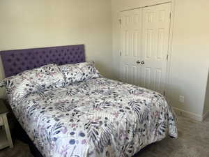 Carpeted bedroom with baseboards and a closet