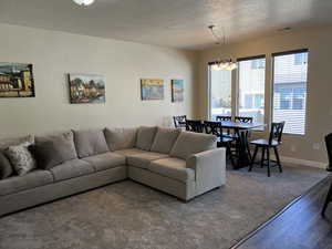 Living room featuring wood finished floors, an inviting chandelier, a textured ceiling, and plenty of natural light