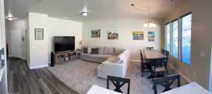 Living area featuring an inviting chandelier, a textured ceiling, dark wood-style floors, and baseboards