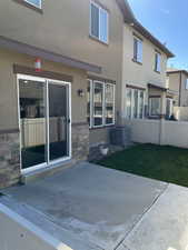 Rear view of property with stucco siding, fence, a patio area, and central air condition unit